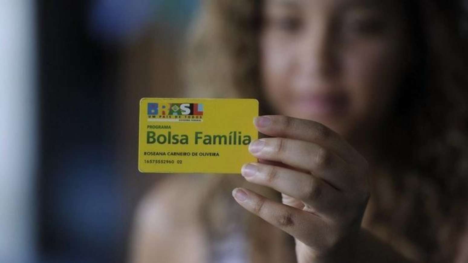 Imagem de uma mulher segurando o cart&atilde;o do programa