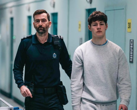 Custodial Manager Bobby Bailey walks beside young inmate Peter Palmerston down a prison corridor