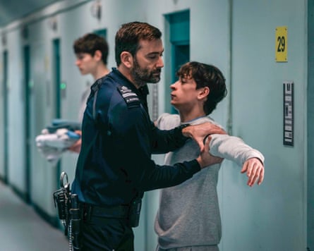 Tennant as a prison guard holding McCartney’s arm, as if searching him