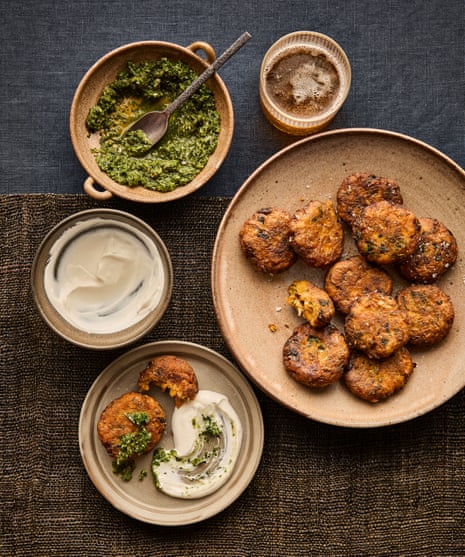 Overhead view of pumpkin and carrot fritters on a plate beside yoghurt and green chilli coriander relish